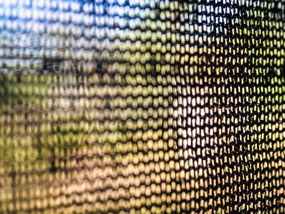 Close-up of shade cloth filtering sunlight for greenhouse cooling